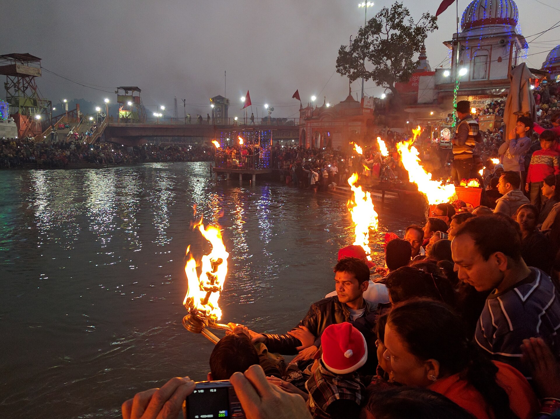 Priest performing Ganga Aarti with a large brass flame